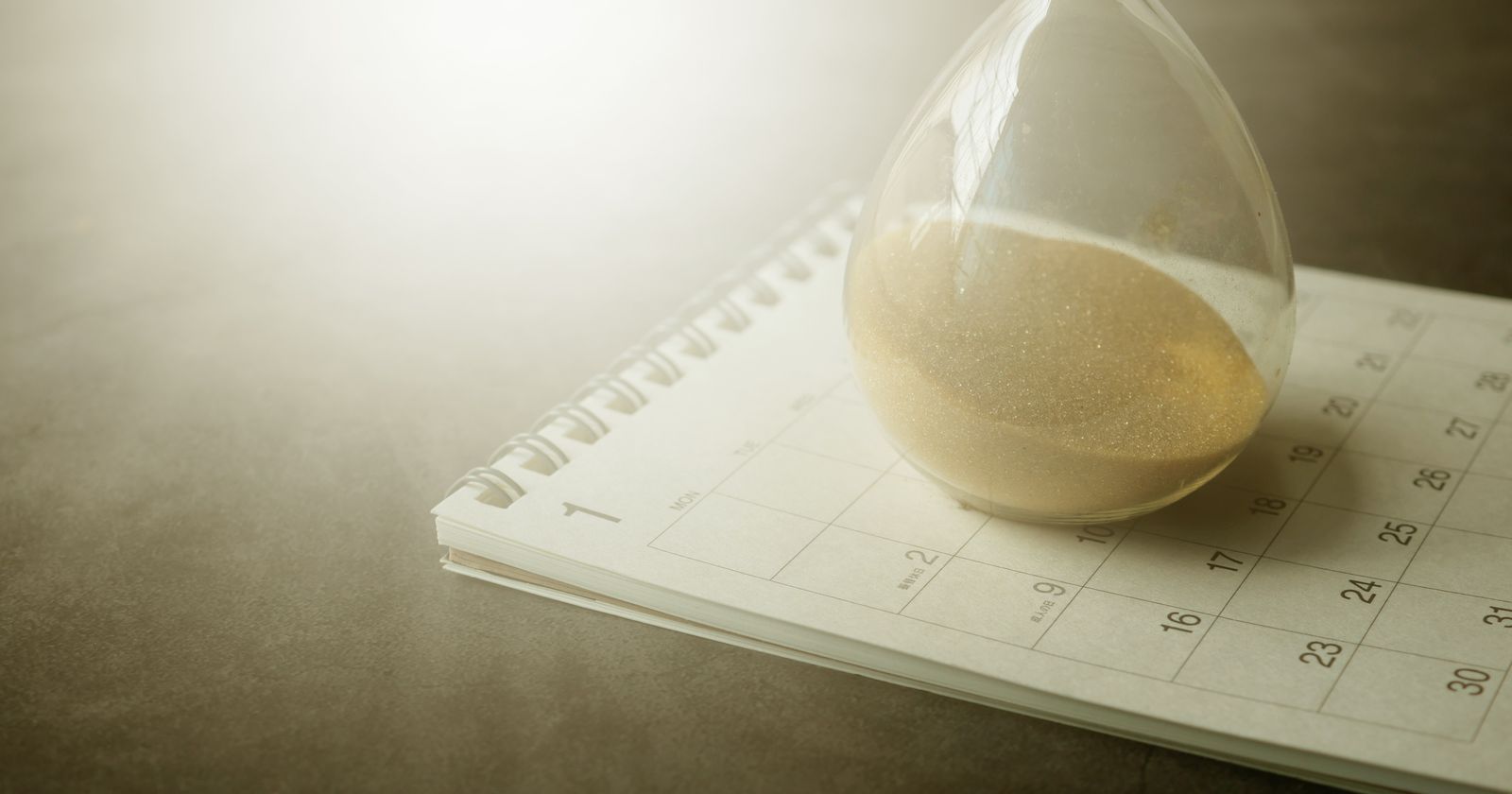 An hourglass resting on a paper calendar, representing the months a nonprofit waits for the IRS to approve its 501(c)(3) application.